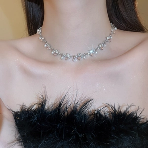 Detail of silver pearl necklace with champagne zircon on model neck against black background
