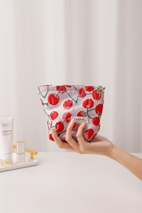 Detail of fabric cosmetic bag with red cherry print and golden flower zipper puller