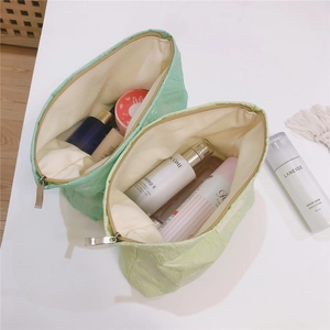 Detail view of large green pleated canvas cosmetic bags with zipper closure and white lining