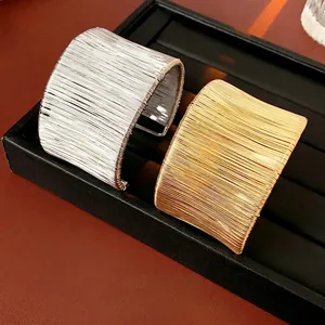 Modern twisted wire wide open cuffs in polished gold and silver metal finishes
