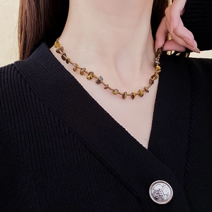 Close-up of tiger eye stone and seed bead necklace on a model with a black V-neck