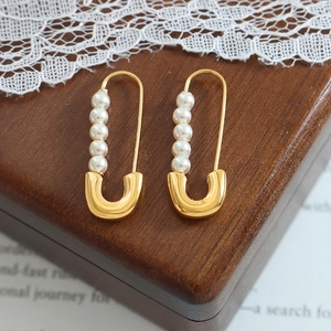Golden safety pin earrings with five round pearls on dark walnut jewelry box