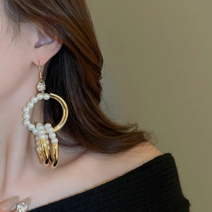Detailansicht goldener Creolen mit weißen Perlen und funkelndem Zirkon im Vintage-Stil