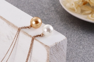 Détail macro de perles dorées et blanches sur une chaîne à maillons en or rose