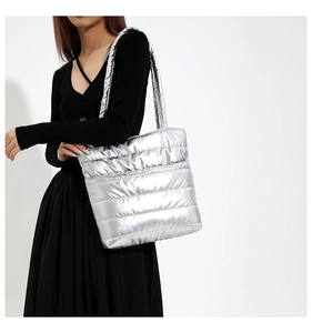 Quilted silver puffer tote bag detail with shiny metallic texture on black dress