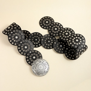 Detail of a black leather eyelet belt with silver round buckle in a wavy S-curve display