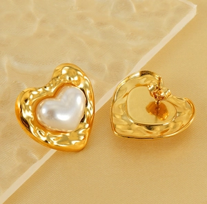 Detail of heart stud earrings with hammered gold metal texture and pearl inlay