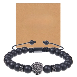 Detail of matte black stone bracelet with silver lion head on kraft paper gift card