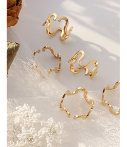 Detailed view of five golden U-shaped wavy open rings on elegant lace background