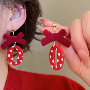 Boucles d'oreilles nœud en velours rouge avec pendentif à motif cœur en vue rapprochée
