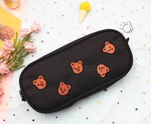 Detail of black canvas pencil case featuring five embroidered orange bear patterns