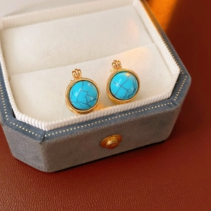 Détail de boucles d'oreilles vintage en résine turquoise et or dans une boîte en velours