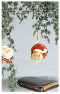 Dettaglio di decorazioni vintage di Babbo Natale in terracotta su rami di pino gelati