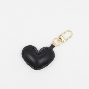 Detailed view of a black heart-shaped PU leather keychain with gold metal hardware