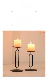 Close-up of minimalist black matte metal candle holders with warm burning pillar candles