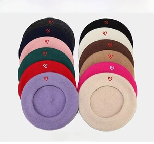 Multiple colors of wool berets with heart embroidery displayed in a neat grid layout