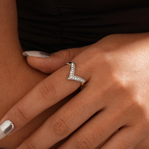 Detailed view of a silver V-shaped ring with pavé set zircons worn on a finger