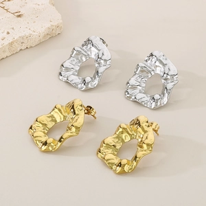 Macro detail of irregular pleated earrings in gold and silver with lava metal texture