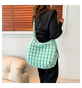 Detailed texture of a mint green quilted puffy shoulder bag styled in a home setting