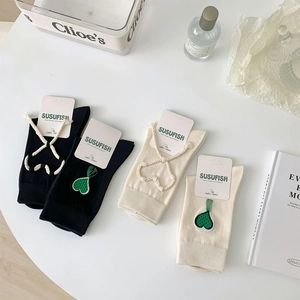 Dettaglio di calze a maglia con allacciatura decorativa e ricamo a cuore verde