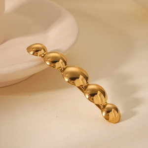 Detail of golden stainless steel hair clip with five polished circular dome designs