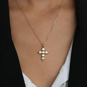 Close-up of model wearing gold cross necklace with six sparkling white zircon stones