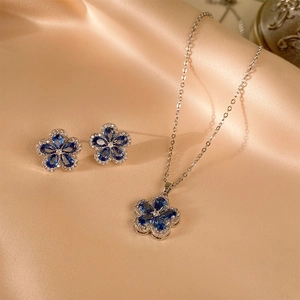 Detailaufnahme von blauem Edelstein-Blumenschmuckset auf Seide mit Halskette und Ohrringen