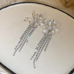 Boucles d'oreilles à fleurs avec glands et cristaux sur une plaque de céramique beige