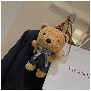 Detail of cute brown plush teddy bear crossbody bag with denim overalls and bow tie
