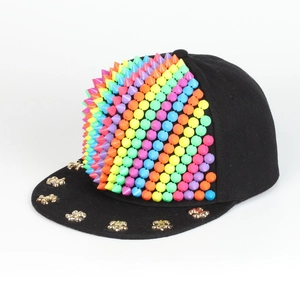Detail der schwarzen Hip-Hop-Kappe mit bunten Silikonspikes und goldenen Lilien-Nieten