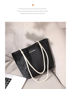 Detail of chevron quilted black tote bag with white rope handle on a modern sofa