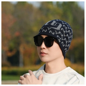 Close-up of navy knit winter hat with gray NY pattern and protective visor brim