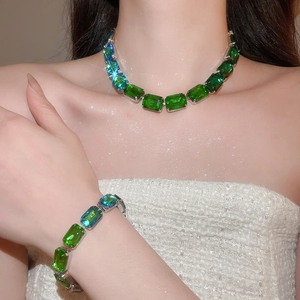 Detailed view of emerald cut green gemstone necklace and bracelet set on model