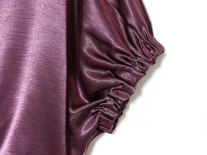 Détail de la manche en satin violet foncé avec poignet élastique et plis délicats