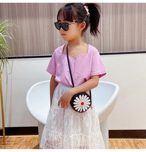 Girl in pink top and white lace skirt carrying a daisy shoulder bag and sunglasses