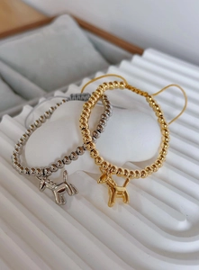 Macro shot of gold and silver balloon dog pendants on adjustable beaded bracelets