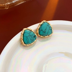 Macro view of triangular turquoise earrings with gold rope textured metal borders