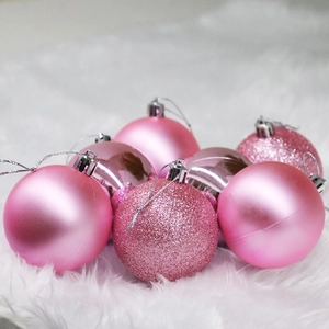 Pink Christmas baubles set with matte, shiny, and glitter finishes on white faux fur background