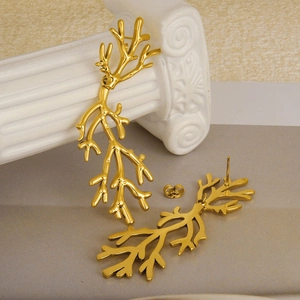 Minimalist branch-shaped 18k gold-plated stainless steel earrings on a classic white column
