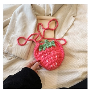 Nahaufnahme der handgestrickten rosa Erdbeertasche mit grünen Blättern und Webstruktur
