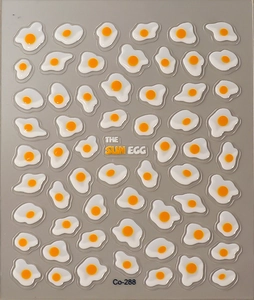 Macro shot of 3D poached egg nail art stickers with glossy texture and Sun Egg text