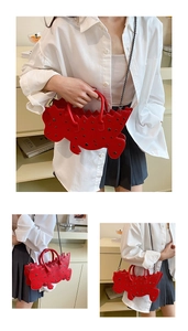 Macro shot of red dinosaur bag with rivet studs and detachable chain shoulder strap