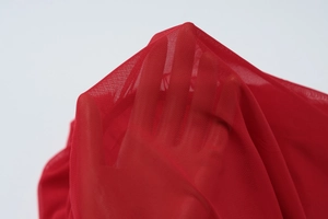 Detail of red sheer mesh fabric showing texture and transparency of the sleeve material