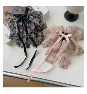 Detail of large floral chiffon bow hair claws in navy blue and soft pink styles