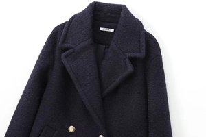 Detail of navy blue tweed coat with gold metal buttons and refined woven texture