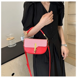 Detail view of red contrast saddle bag with woven texture lid and golden metal clasp