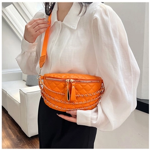 Close-up of orange quilted waist bag with gold chain accents and a wide fabric strap