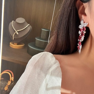 Detail of elegant leaf tassel earrings with sparkling red zircons worn by a model