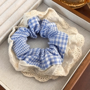 Detail of blue plaid hair scrunchie with lace trim and silver sequins in jewelry box
