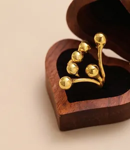 Detailed view of gold steel ring with bean motifs in a heart-shaped wooden gift box